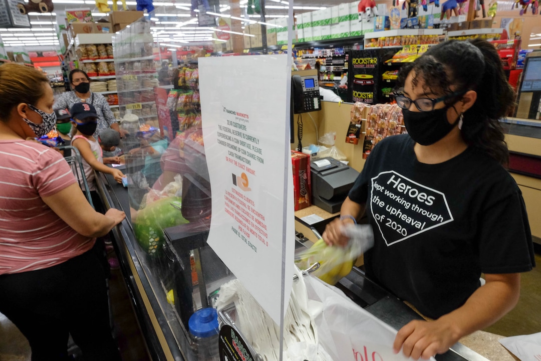 (Francisco Kjolseth  |  The Salt Lake Tribune) Yuderca Rosario checks people out from behind a plexiglass wall as Rancho Markets implement numerous safety precautions at their stores to navigate the coronavirus pandemic as people shop at the 140 N. 900 West location in Salt Lake City on Friday, August 14, 2020.