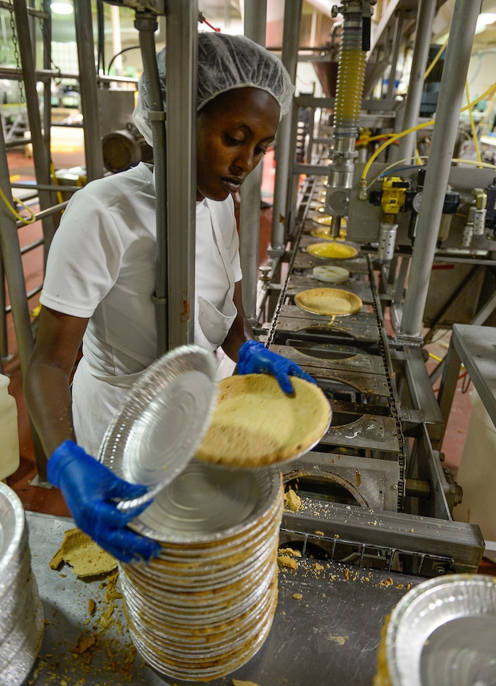 Francisco Kjolseth | The Salt Lake TribuneGentille Uwitonze hand places pie crusts on an assembly line machine during a production run of lemon meringue pies at Rocky Mountain Pie factory in Salt Lake recently. 