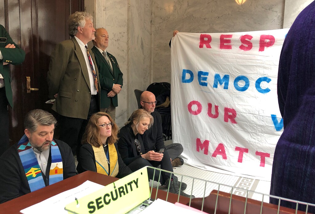 (Lindsay Whitehurst | The Associated Press) Religious leaders demonstrating against Utah lawmakers' efforts to scale back a voter-approved expansion of Medicaid sit in front of the entrance to the Utah House of Representatives singing protest songs as legislators debate the bill in Salt Lake City, Friday, Feb. 8, 2019. Counter protesters in favor of the bill are also on hand in Salt Lake City.