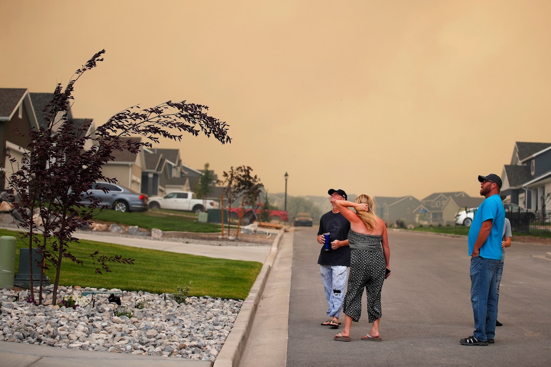 (George Frey  |  for The Salt Lake Tribune) As high winds bend a tree limb, people watch from their homes in south Saratoga Springs as a nearby wildfire burns on June 28, 2020.