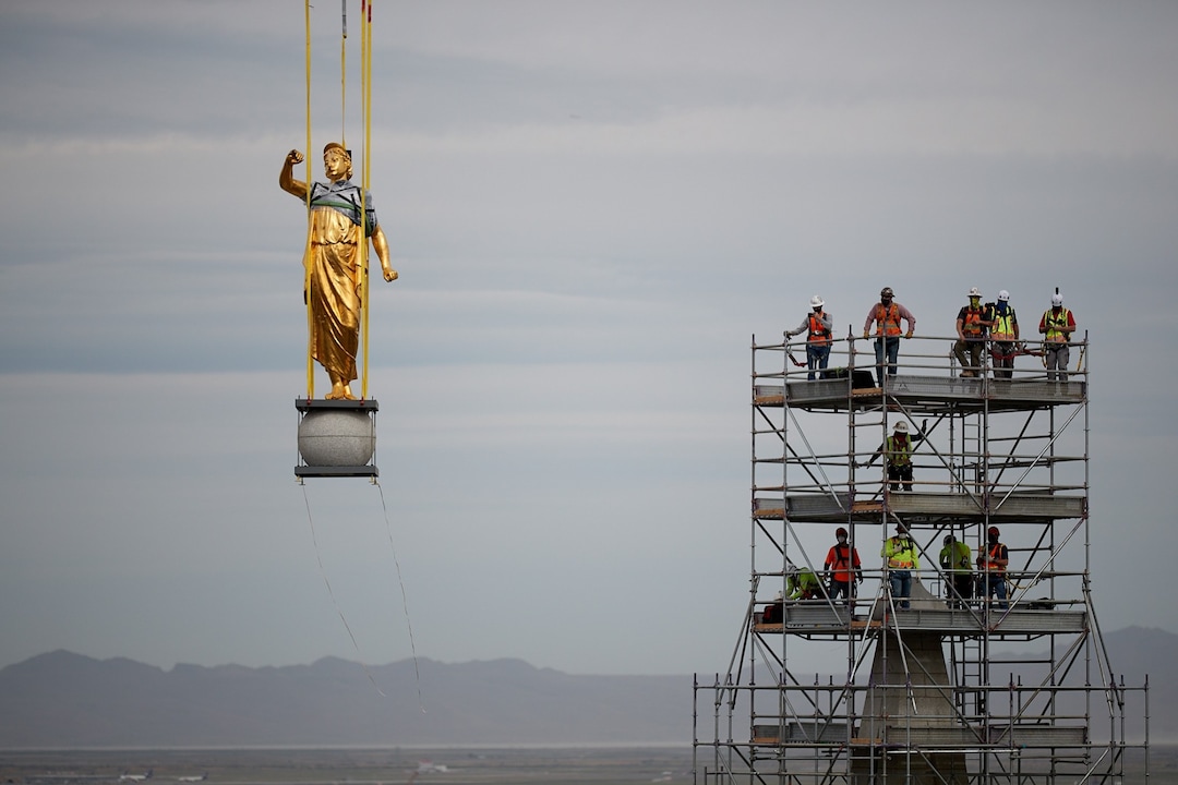 (Photo courtesy of The Church of Jesus Christ of Latter-day Saints) The angel Moroni and capstone being removed by a large crane with artisan journeyman viewing in the background as part of the ongoing renovation of the Salt Lake Temple, May 18, 2020.