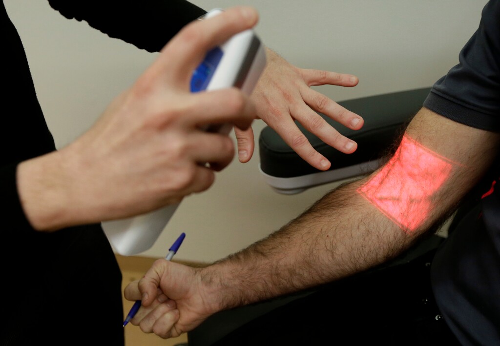 In this Jan. 10, 2017 photo, Adrian Aoun, founder and CEO of Forward, left, gives a demonstration of a vein illumination device that uses infrared light on an Associated Press reporter at a medical office in San Francisco. After a relative suffered a heart attack a few years ago, Silicon Valley entrepreneur Aoun got an up-close look at a health-care system that he diagnosed as an inefficient and outdated mess. Now, Aoun is ready to prescribe his remedy. It's called Forward, a health-management service that charges a $149 per month, roughly $1,800 a year, to tend to all of its patients' primary-care needs. (AP Photo/Jeff Chiu)