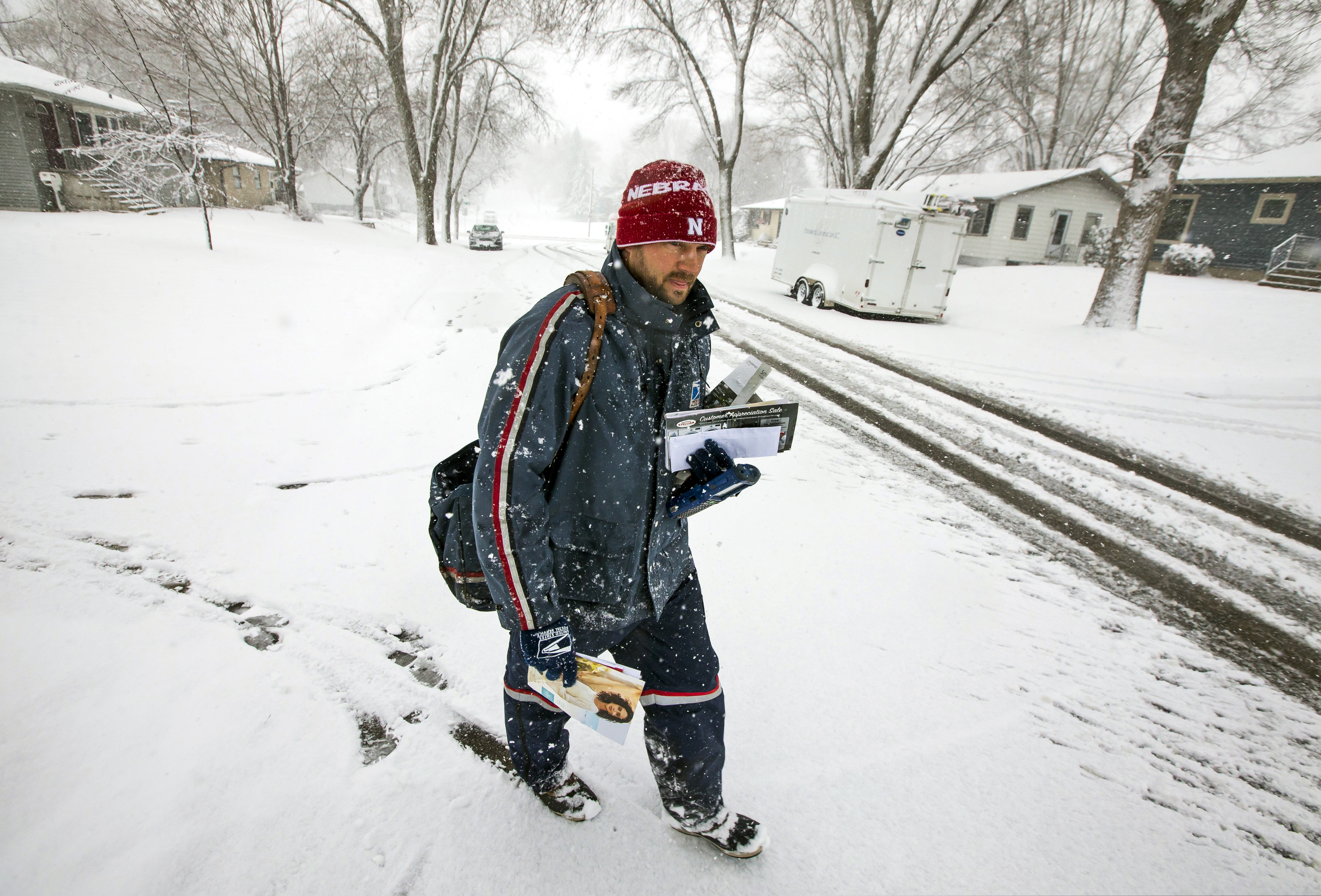 (Andrew Link | The Rochester Post-Bulletin | AP) United States Postal Service city carrier Chad Jacobs delivers mail along 16th Avenue Northwest as snow falls, Wednesday, April 10, 2019, in Rochester, Minn. Jacobs said he doesn't mind cold and prefers it over hot days.