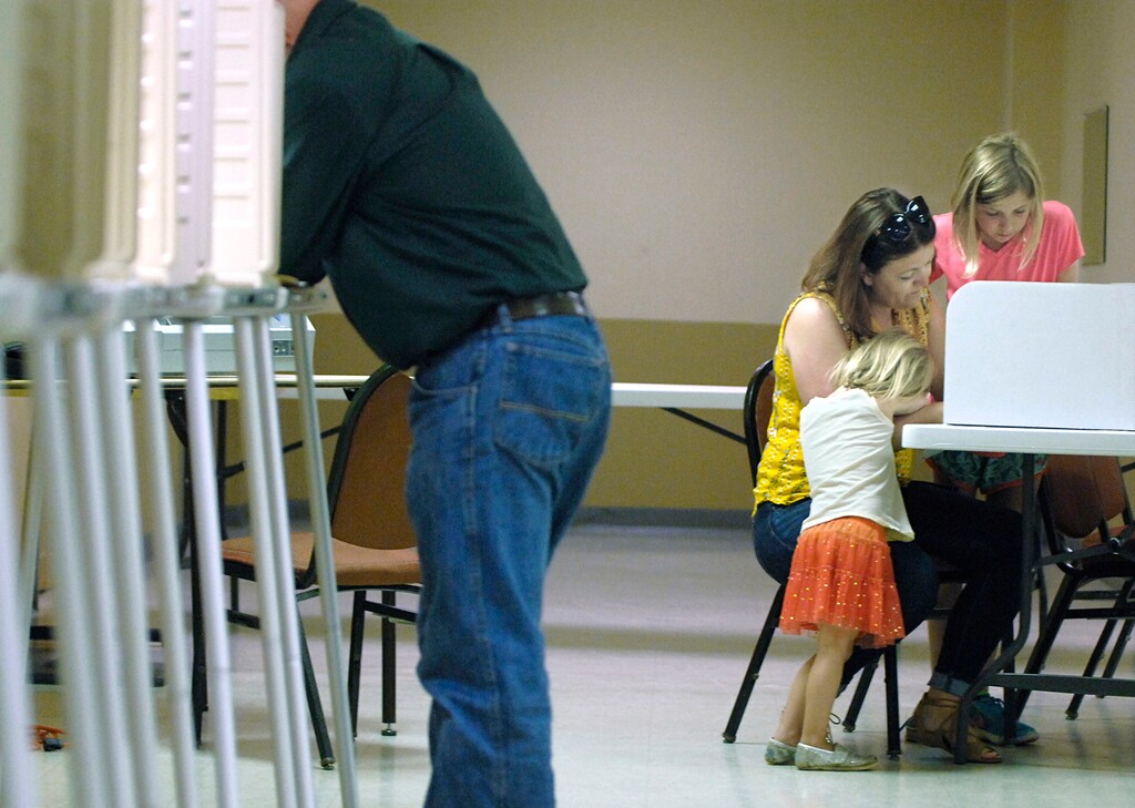 (Mike Mccleary | The Bismarck Tribune | The Associated Press) Tenleigh Jackson, 4, patiently waits as her mother, Tanya, fills out her ballot with her sister, Lynnea, 10, watching during primary election voting at the Eagles Club for District 34 in Mandan, North Dakota on on Tuesday, June 12, 2018.
