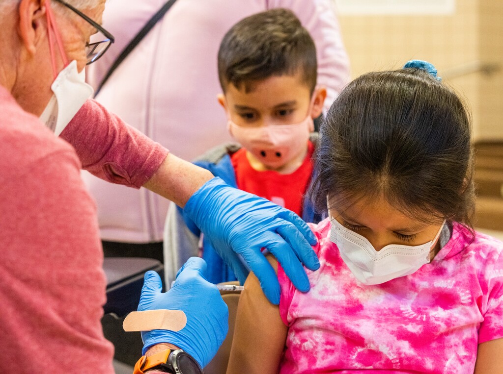 (Rick Egan | The Salt Lake Tribune) Christopher Marroquin watches as Curtis Evans administers a COVID-19 vaccine to his sister, Genesis Marroquin, at Midvale Elementary School, on Wednesday, January 26, 2022. COVID-19 vaccines are expected to be approved for children ages 5 years and younger in the coming days.