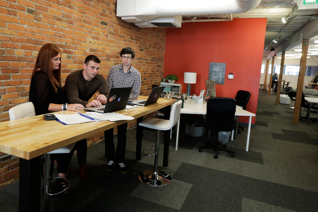 (Ted S. Warren | AP) In this Tuesday, Sept. 10, 2019, photo Shane Griffiths, right, and Trenton Erker, center, co-owners of the digital marketing company Clarity Online, work with one of their clients, Susan Leeming, the owner of High Maintenance Spa and Salon in Tacoma, Wash., in their company's workspace in Seattle.