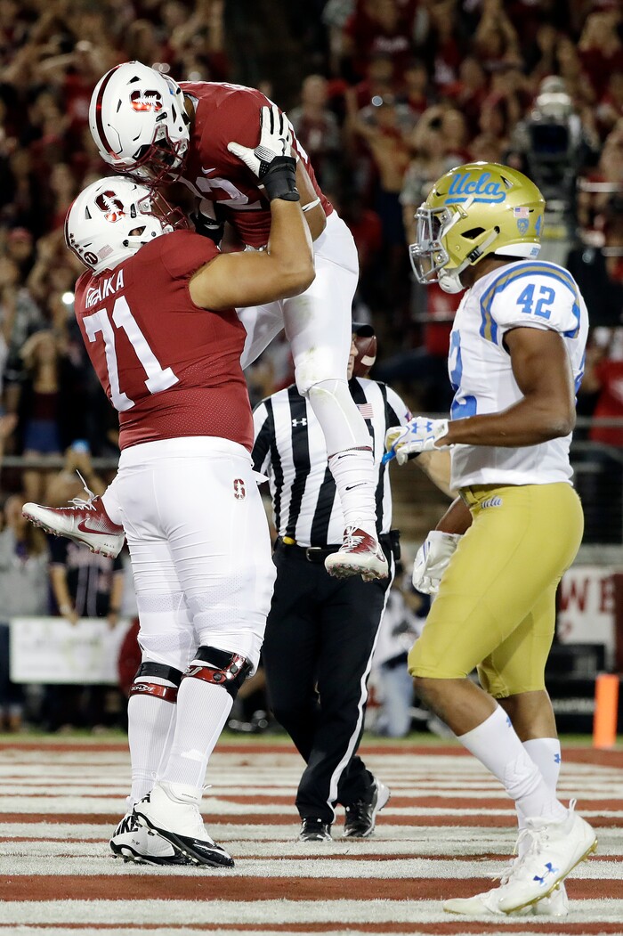 Stanford running back Cameron Scarlett, center, is lifted by Brandon Fanaika (71) after Scarlett's rushing touchdown against UCLA during the first half of an NCAA college football game Saturday, Sept. 23, 2017, in Stanford, Calif. (AP Photo/Marcio Jose Sanchez)