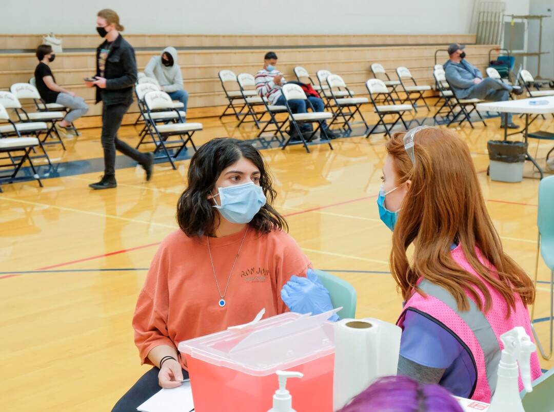 (Leah Hogsten | The Salt Lake Tribune) Sara Sharma, 16, a student at Woods Cross High School, misses her Spanish class to receive her first Pfizer vaccine from Pharmacist Shannon Stoker at a pop-up clinic by Nomi Health,  April 27, 2021. County and regional health districts are setting up vaccination clinics in high schools, to get the COVID-19 vaccine to 16 and 17-year-olds.