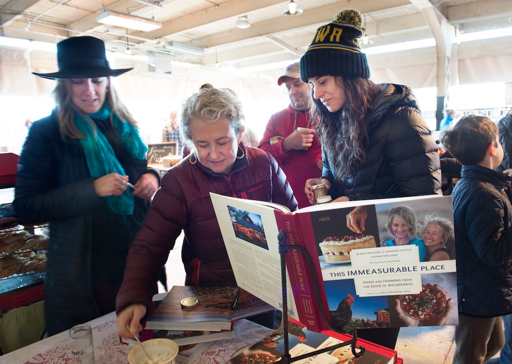 (Scott Sommerdorf | The Salt Lake Tribune) Jen Castle, left, and Blake Spalding, center, owners of Hell's Backbone Grill in Boulder, sign copies of their new cookbook, "This Immeasurable Place: Food and Farming from the Edge of Wilderness," at the Winter Market at the Rio Grande Depot, Saturday, December 9, 2017.