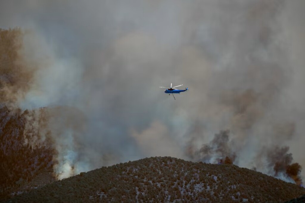 (Trent Nelson | The Salt Lake Tribune) A helicopter crew flies over the Cottonwood Fire burning near Beaver.