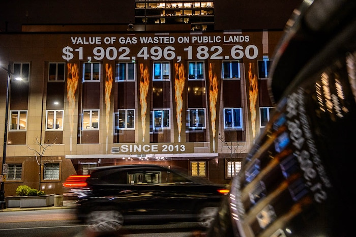 (Trent Nelson | The Salt Lake Tribune)
In a visual protest, Alliance for Better Utah projects the total dollar value of natural gas lost on public lands since 2013 due to venting, flaring, and leaking onto the side of Federal Reserve Building in Salt Lake City, Thursday April 5, 2018.