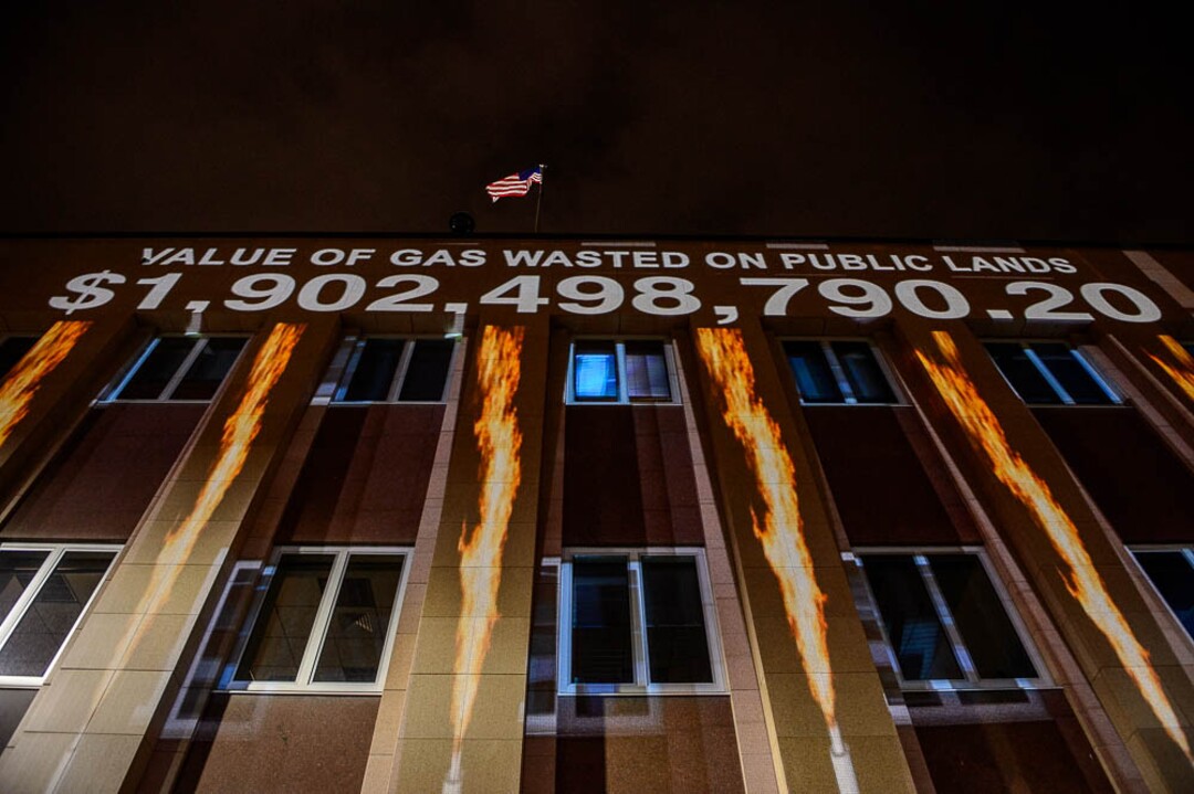(Trent Nelson | The Salt Lake Tribune)  In a visual protest, Alliance for Better Utah projects the total dollar value of natural gas lost on public lands since 2013 due to venting, flaring, and leaking onto the side of Federal Reserve Building in Salt Lake City, Thursday April 5, 2018.