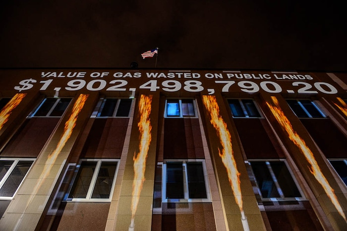 (Trent Nelson | The Salt Lake Tribune)
In a visual protest, Alliance for Better Utah projects the total dollar value of natural gas lost on public lands since 2013 due to venting, flaring, and leaking onto the side of Federal Reserve Building in Salt Lake City, Thursday April 5, 2018.