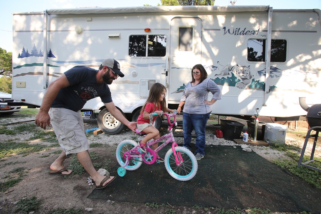 (Jerry Larson  | for The Salt Lake Tribune)  Tyler Rowley pushes his daughter, Mykari, 4, as her mother, Courtney, looks on outside their travel trailer, Thursday, August 31, 2017, in Clifton, Texas. The family left Utah after Tyler Rowley lost a mining job and struggled to find permanent work that paid as well and was near their home in Castle Dale.