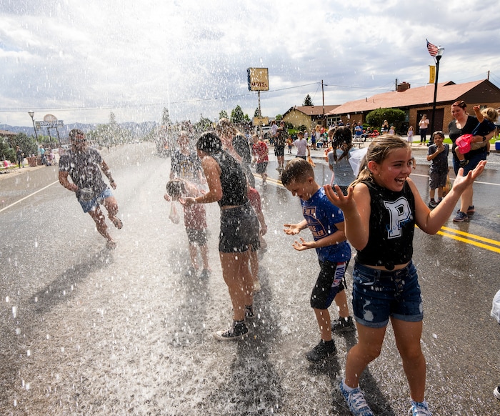 (Rick Egan | The Salt Lake Tribune) Kids flock to the middle of Center Street in Panguitch to cool down in water from the fire truck during the Pioneer Day Parade, on Saturday, July 23, 2022. 
