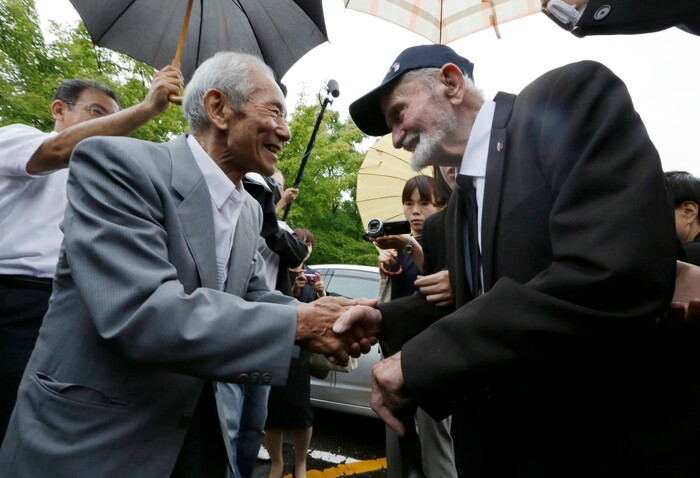 Tatsuya Yasue, left, and WWII veteran Marvin Strombo shake hands prior to a ceremony in Higashishirakawa, in central Japan's Gifu prefecture Tuesday, Aug. 15, 2017. Strombo returned a Japanese flag with autographed messages which was owned by Tatsuya's brother Sadao Yasue, who was killed in the Pacific during World Work II. (AP Photo/Eugene Hoshiko)