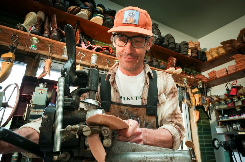 (Bethany Baker  |  The Salt Lake Tribune) Owner Dax Williamson cuts a piece of leather in Lucky Sole Shoe Repair in Lehi on Thursday, April 17, 2025.