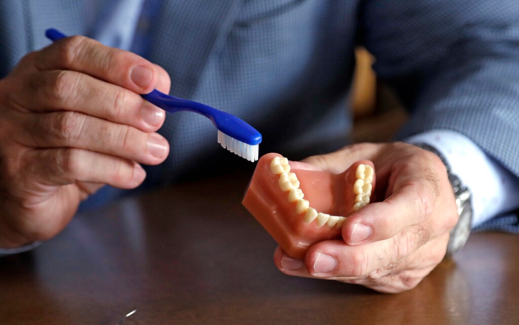 In this photo taken Friday, Aug. 3, 2018, Philippe Hujoel, a dentist and University of Washington professor, holds a model of teeth and a toothbrush as he talks in an office at the school in Seattle. Dental health experts worry that more people are using toothpaste that skips the most important ingredient - the fluoride - and leaves them at a greater risk of cavities. (AP Photo/Elaine Thompson)
