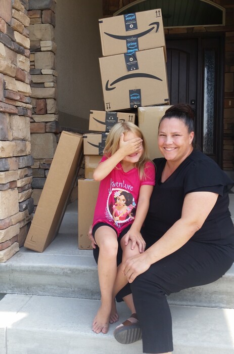 (Photo courtesy Catherine Lunt) Catherine Lunt and her 6-year-old daughter Katelyn sit on the front step of their home in Pleasant View, Utah, with the many packages of Barbie dolls and accessories Katelyn recently ordered when her mom wasn't looking. The spending spree became an internet sensation.