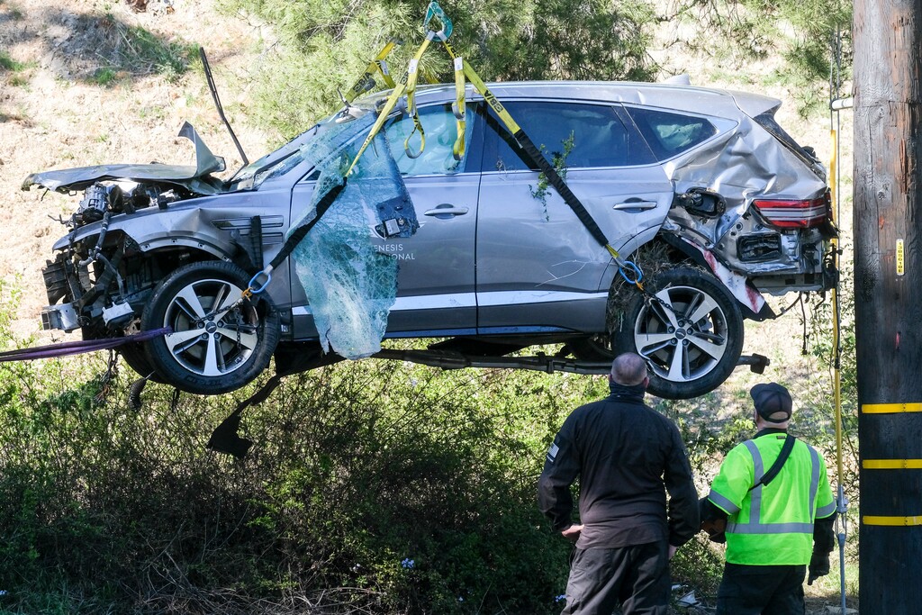 (Ringo H.W. Chiu | AP) A crane is used to lift a vehicle following a rollover accident involving golfer Tiger Woods, in the Rancho Palos Verdes suburb of Los Angeles, Feb. 23, 2021. Authorities said Wednesday, April 7, Woods was speeding when he crashed leaving him seriously injured.