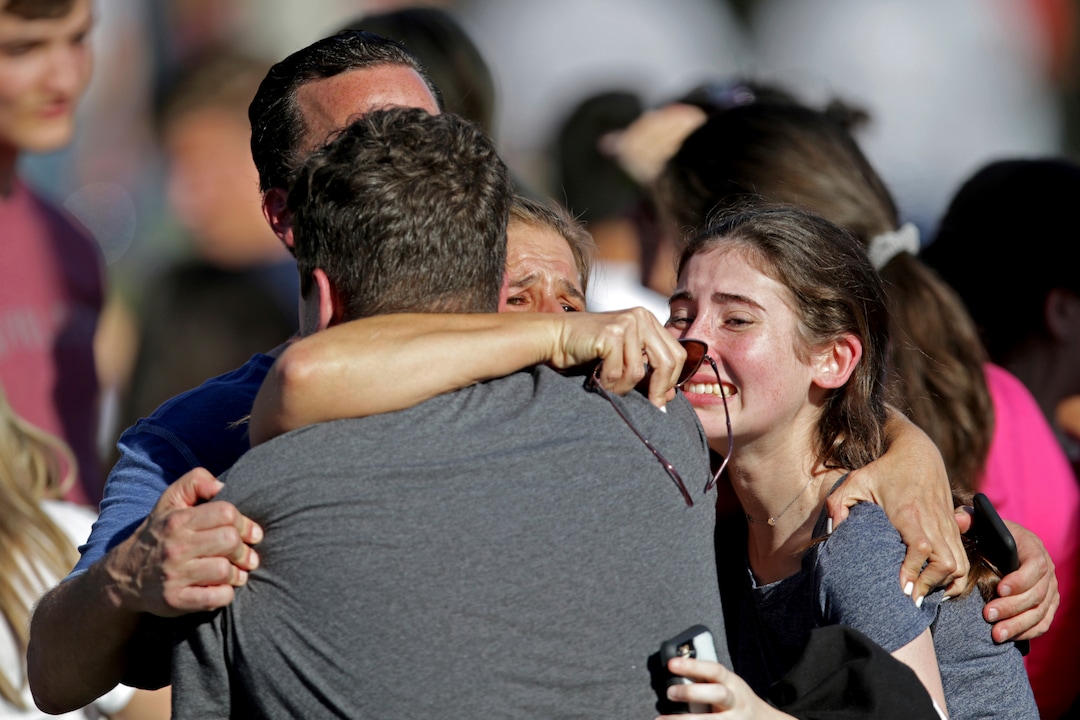 A family reunites following a shooting at Marjory Stoneman Douglas High School in Parkland, Fla., Wednesday, Feb. 14, 2018. (John McCall/South Florida Sun-Sentinel via AP)