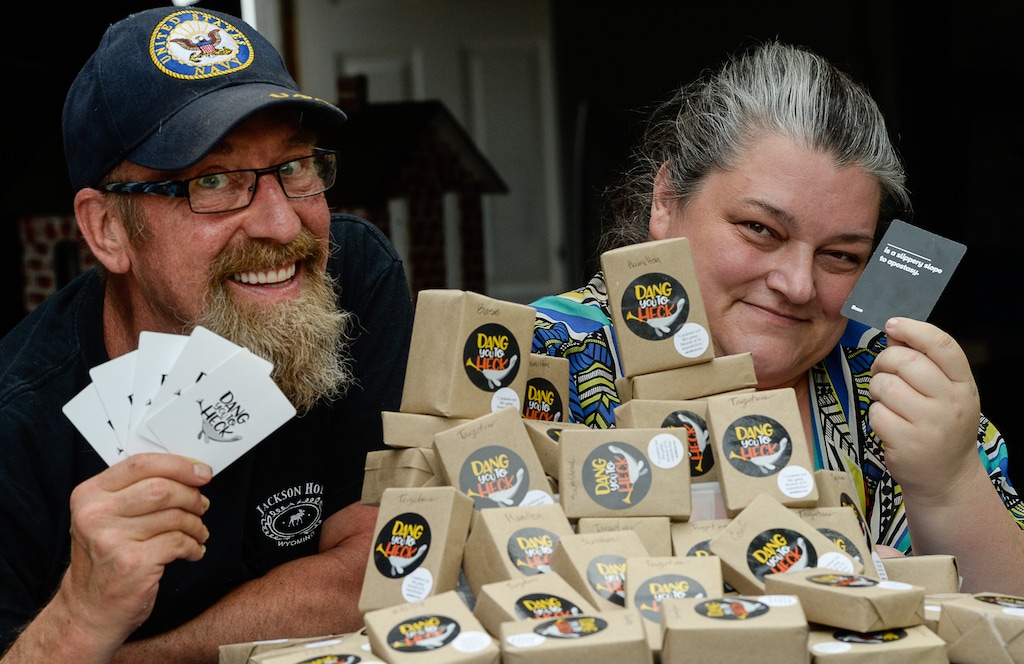 (Francisco Kjolseth | The Salt Lake Tribune) Dang You to Heck, billed as a family-friendly, Utah-themed alternative to Cards Against Humanity and other NSFW card games is the creation of Jerilyn Pool, of Provo, with an assist from her husband Jeff who were recently assembling themed collections at their home on Thursday, Aug. 3, 2018. Jerilyn holds up a card that reads "...is a slippery slope to apostasy."