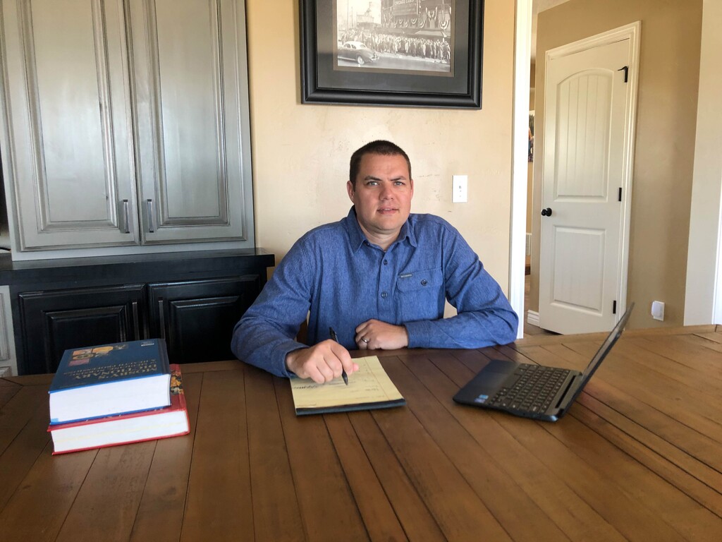 (Courtesy Institute for Justice) Jeremy Barnes sits at a table in his home in Franklin, Idaho. Barnes, a former police officer, wants to work as a private investigator in Utah — but state officials say he can't because he doesn't live in the state. He has filed a lawsuit hoping to change the residency requirement.