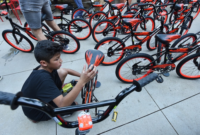 (Francisco Kjolseth  |  The Salt Lake Tribune)  Angel Fernandez, 11, fills bicycle tires with air as he joins other volunteers and workers at Squatter's Pub Brewery to assemble 80 bicycles on Tuesday, May 29, 2018, at the brewery which will be given away to 1st and 2nd graders at Washington Elementary on Wednesday. Part of the program is backed by the Can'd Aid Foundation.