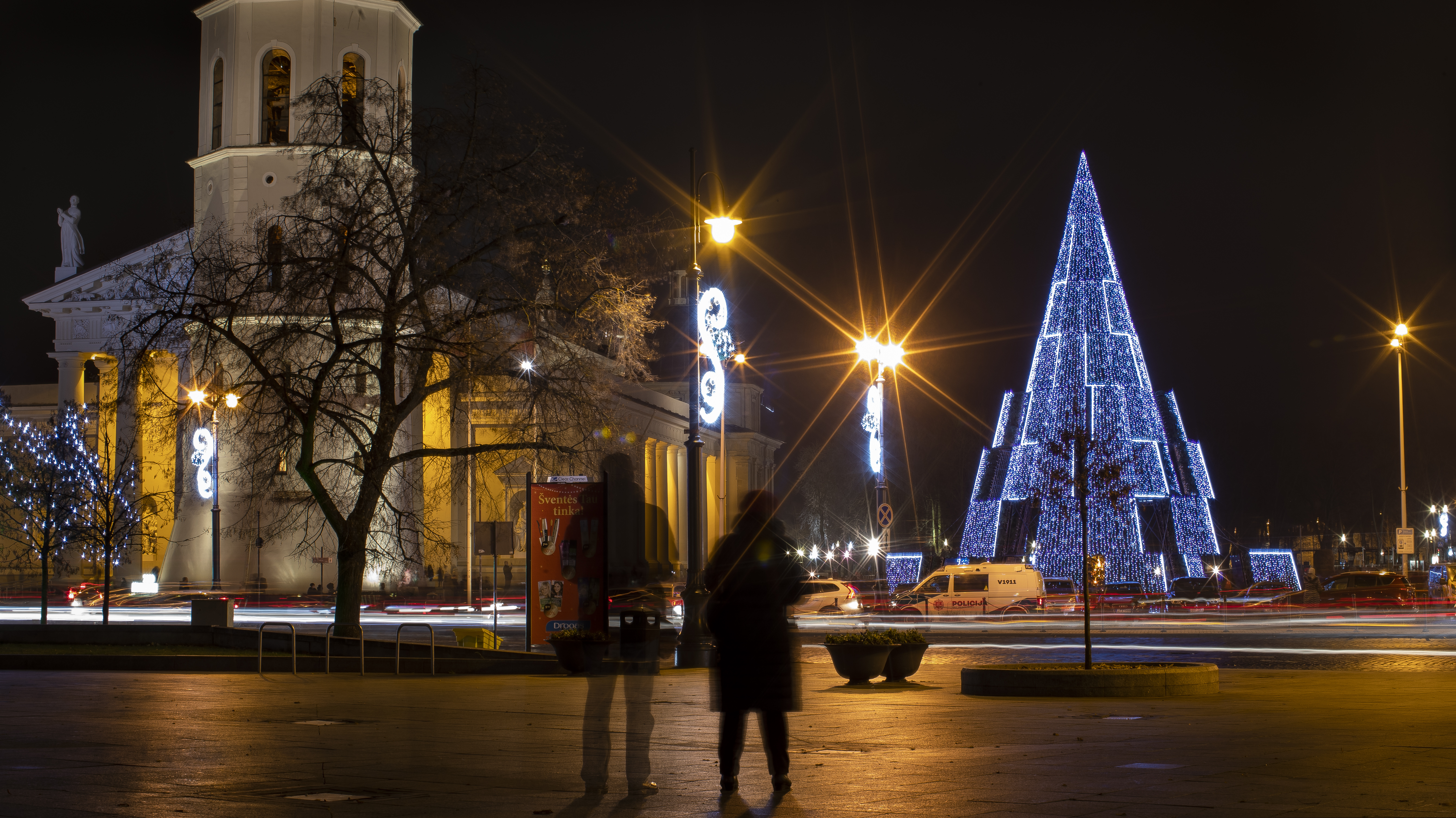 (AP Photo/Mindaugas Kulbis) Visitors look at the Christmas tree in Cathedral Square in Vilnius, Lithuania, Saturday, Dec. 5, 2020.