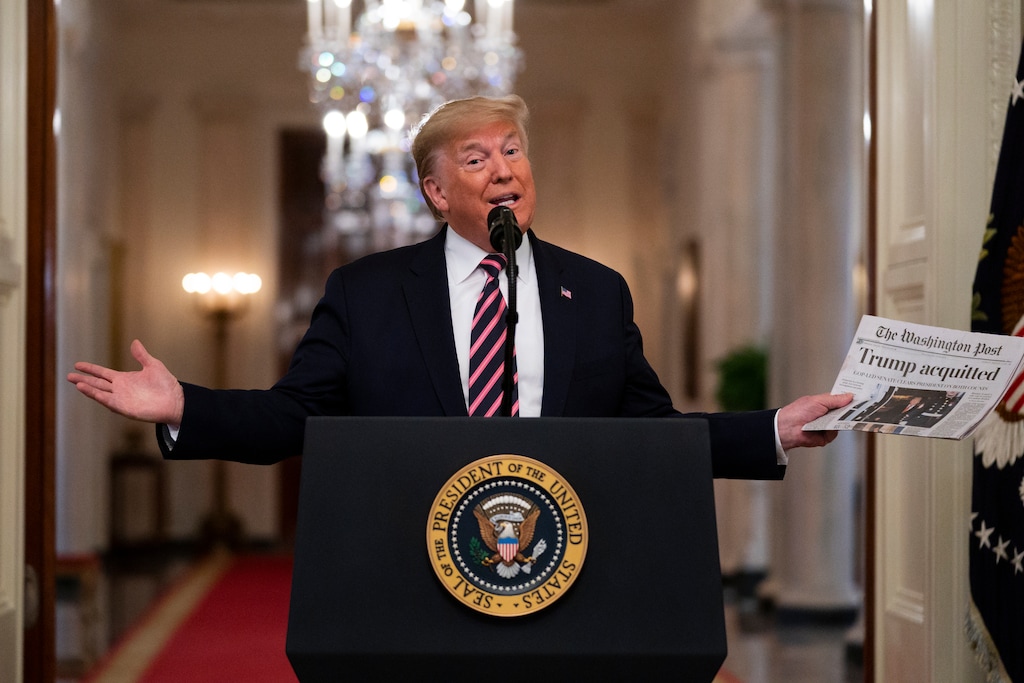 (AP Photo | Evan Vucci) President Donald Trump holds up a newspaper tat reads "Trump acquitted" during during an event celebrating his impeachment acquittal, in the East Room of the White House, Thursday, Feb. 6, 2020, in Washington.