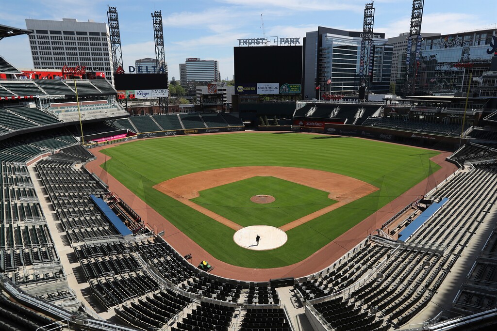 FILE - In this April 1, 2020, file photo, Atlanta Braves field manager Tyler Lenz walks across the covered home plate at Trust Park in Atlanta. There are no sponsored power plays at the moment. No doughnut races in the fourth quarter. No calls to the bullpen presented by phone companies. While the coronavirus pandemic circles the world, sports business executives are having conversations about lucrative advertising and marketing contracts with no games on the horizon. (Curtis Compton/Atlanta Journal-Constitution via AP, File)