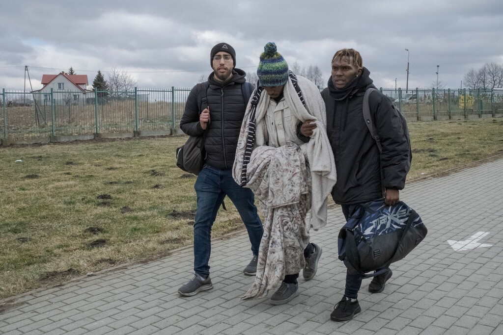 (Mauricio Lima | The New York Times)
Martin Mpofu, center, a student from Zimbabwe in weak health, is helped by his brother Maneedi, right, and Hatim Redouani, from Morocco, as they cross from Ukraine into in Medyka, Poland, Feb. 28, 2022. Africans who had been living in Ukraine say they were stuck for days at crossings into neighboring European Union countries, held up by Ukrainian authorities who pushed them to the ends of long lines and even beat them, while letting Ukrainians through.