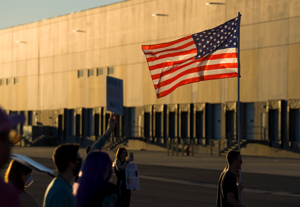 (Bethany Baker | The Salt Lake Tribune) An American flag flies during a protest at the Salt Lake City warehouse purchased by ICE, Wednesday, March 18, 2026. An internal ICE memo offers clues to how the facility may be used in a national detention network.
