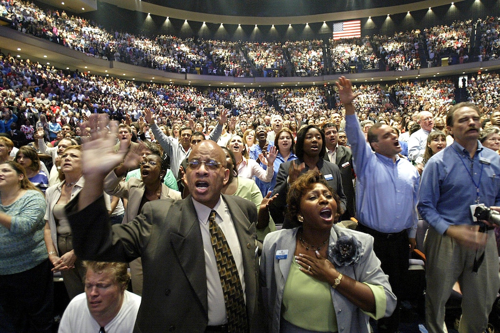 (Jessica Kourkounis | AP file photo) In this July 16, 2005, file photo, members of the Lakewood Church worship at the grand opening of their megachurch in Houston.
