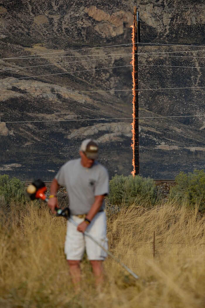 (Francisco Kjolseth  |  The Salt Lake Tribune)  The community comes together to cut down tall brush as crews battle a grass fire in Tooele county being dubbed the Green Ravine fire as it burns on Tuesday, Sept. 3, 2019.