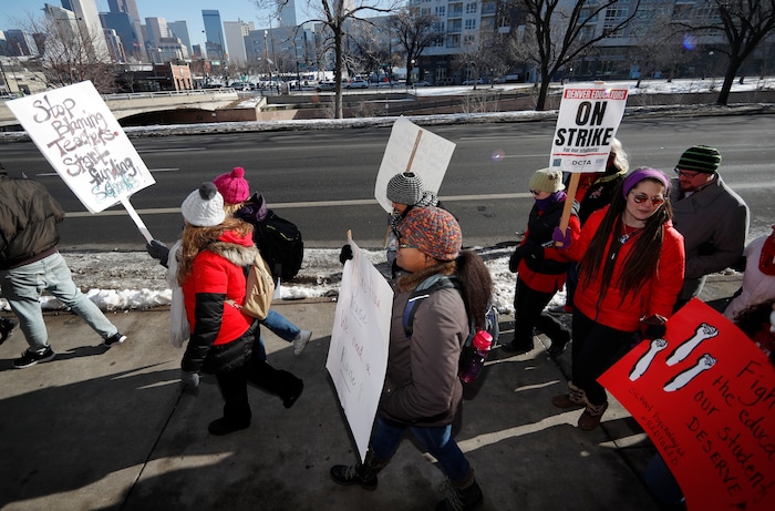 Teachers carry placards as they march along Speer Boulevard from West High School Monday, Feb. 11, 2019, in Denver. Denver teachers went on strike Monday after failing to reach a deal with administrators on pay in the latest example of educator discontent, following a wave of walkouts over the last year. (AP Photo/David Zalubowski)