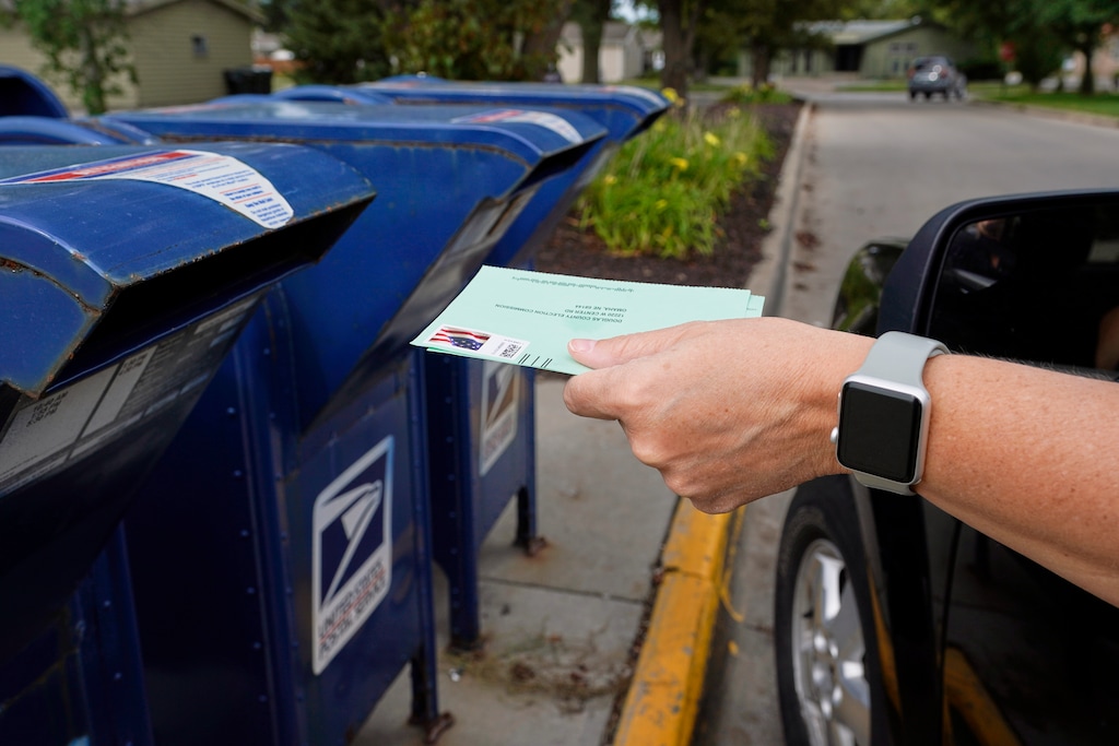 (Nati Harnik | AP file photo)  A person drops into a mailbox applications for mail-in ballots, in Omaha, Neb., Tuesday, Aug. 18, 2020.
