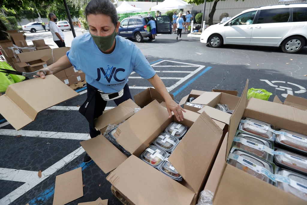 (Wilfredo Lee | AP) Volunteer Malka Rodrig unpacks meals at a kosher food drive-thru distribution site, Wednesday, July 29, 2020, at the Greater Miami Jewish Federation building in Miami.