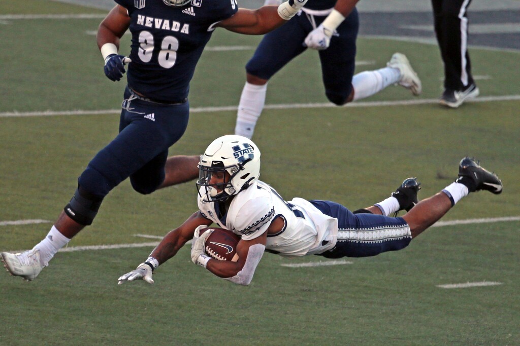 Utah State quarterback Jason Shelley (15) stretches out for more yards after being tripped up during the first half of an NCAA college football game against Nevada on Thursday, Nov. 5, 2020, in Reno, Nev. (AP Photo/Lance Iversen)