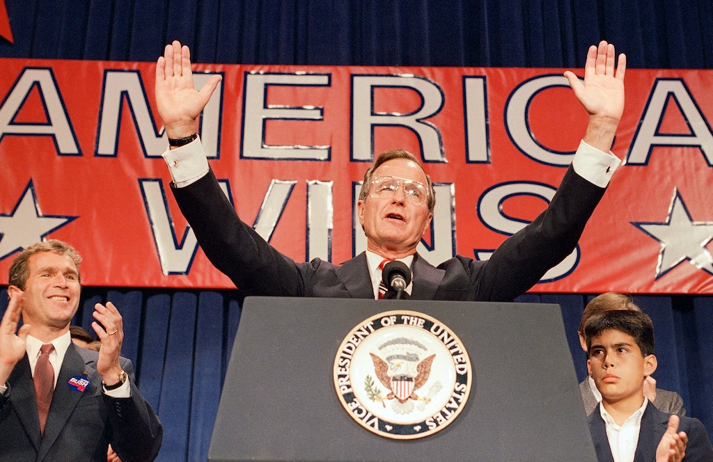 (The Associated Press) In this Nov. 9, 1988 file photo, President-elect George H. W. Bush holds his hands up to acknowledge the crowds applause, and ask them to allow him to continue his speech, during his victory rally with grandson, George P. Bush, right, and son George W. Bush, left, in Houston, Texas.  The Kennedys had their New England coastal hideaway in Hyannis Port, a Camelot-like mystique and a political godfather in Joseph P. Kennedy. For the country's other political dynasty, the Bushes ,  it was a summer home in Maine and the West Texas oil patch that created a mix of Yale blue-blood and backcountry cowboy. Their patriarch was George H.W. Bush, a World War II hero, Texas congressman, the director of the CIA, vice president and eventually president.