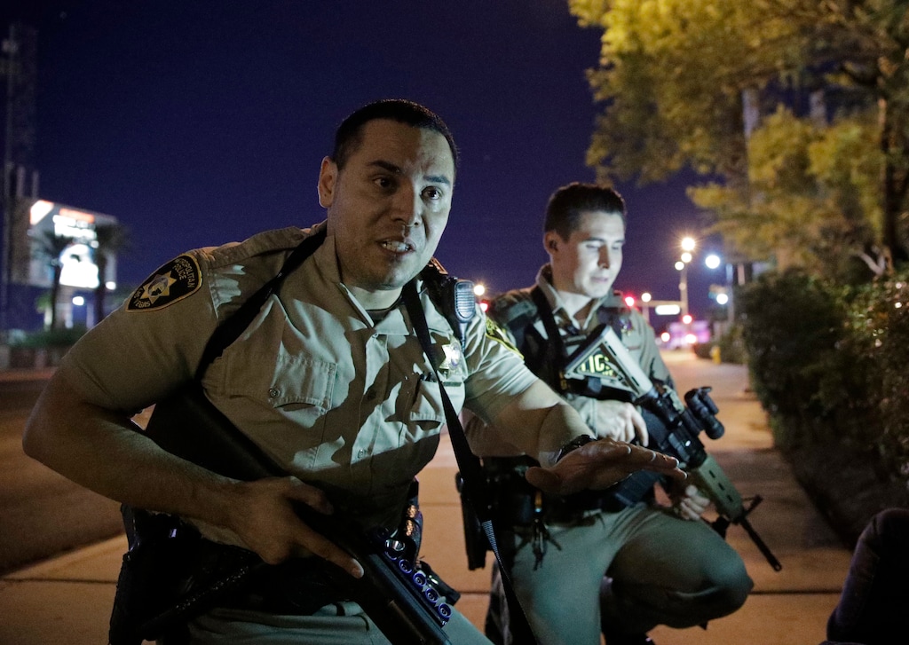 Police officers advise people to take cover near the scene of a shooting near the Mandalay Bay resort and casino on the Las Vegas Strip, Sunday, Oct. 1, 2017, in Las Vegas. (AP Photo/John Locher)