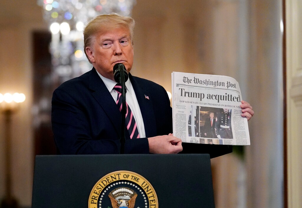 (Evan Vucci | AP Photo) President Donald Trump holds up a newspaper with a headline that reads "Trump acquitted" as he speaks in the East Room of the White House, Thursday, Feb. 6, 2020, in Washington.