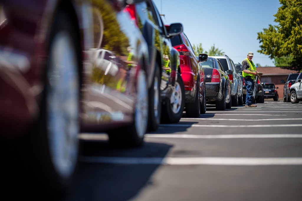 (Trent Nelson  |  The Salt Lake Tribune) Volunteer Steven Hurst walks a long line of cars at a mobile food pantry sponsored by Utah Food Bank in Taylorsville on Monday, June 26, 2023