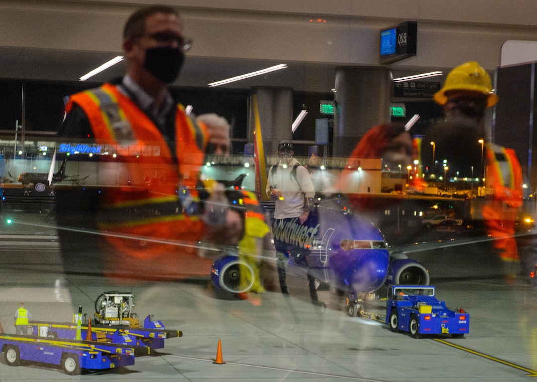 (Trent Nelson  |  The Salt Lake Tribune) Workers reflected in the window look on as the first flight from concourse B at the Salt Lake City International Airport, a Southwest flight to Oakland, prepares to take off on Tuesday, Oct. 27, 2020.