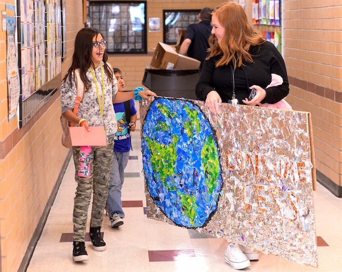 (Leah Hogsten  |  The Salt Lake Tribune) l-r Andrea Perez and her teacher Cher Sten shares a laugh while transporting the plastic trash mosaic through the school.  Students at Parkview Elementary have created a treasure with trash. Ten fifth graders in Cher Sten's extended learning program or ELP class, molded school and household plastic refuse into a mosaic to send the message: "Consume Less" to their classmates. The idea for the mural began after a discussion about global warming, climate issues, plastic pollution and its implications on earth.