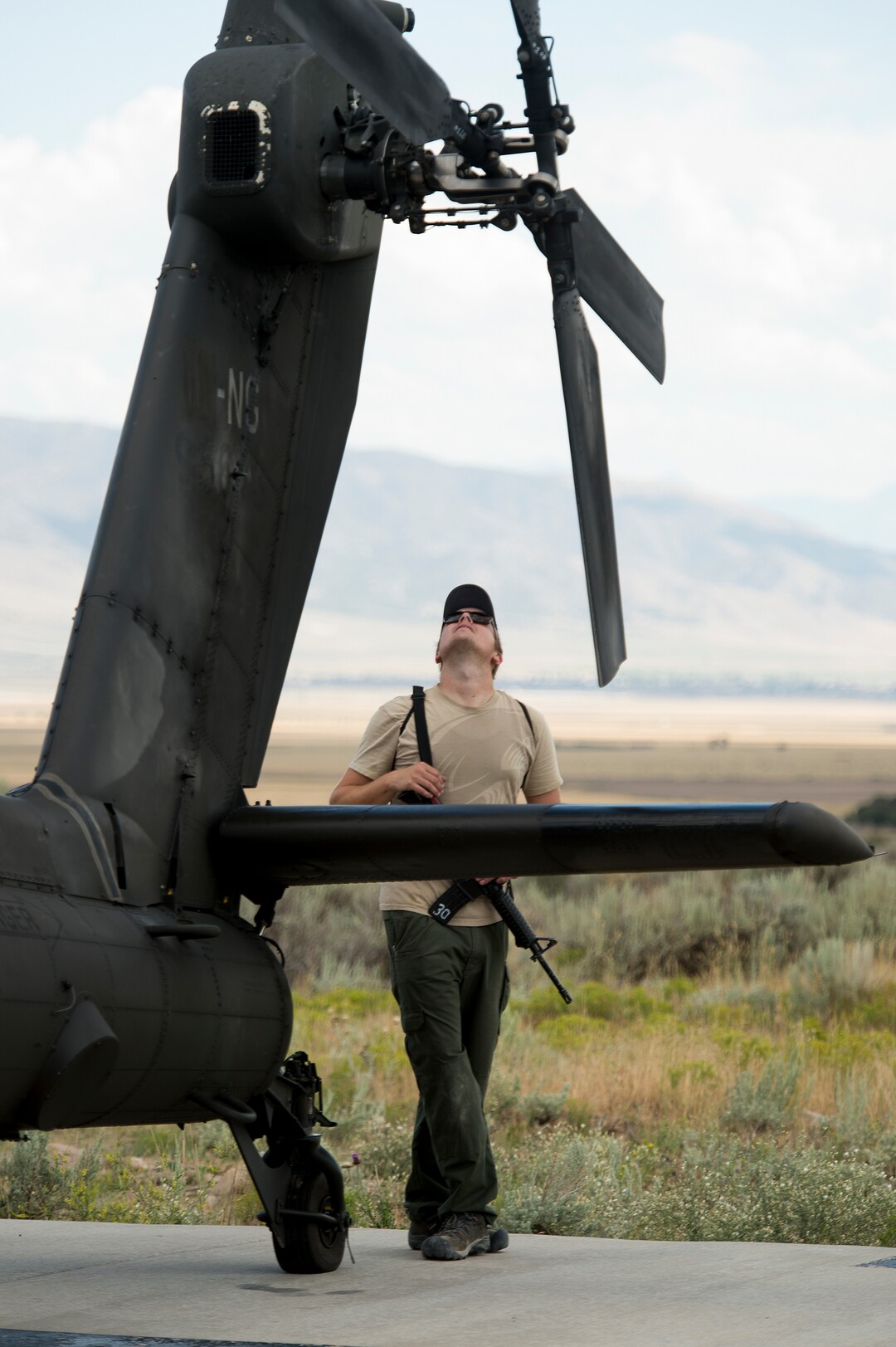 (Leah Hogsten  |  The Salt Lake Tribune) Evan Floodman, 29, of Wanship walks around an AH-64 Apache Attack helicopter from the 211th Aviation Group during the Utah National Guard Special Forces Survival Training Experience, August 10-12, 2017 at Camp Williams. 