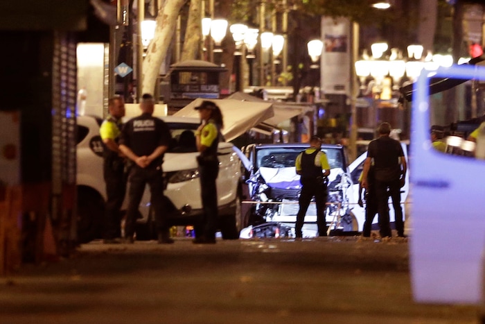 (Manu Fernandez | The Associated Press) Police officers stand next to the van involved on an attack in Las Ramblas in Barcelona, Spain, Thursday, Aug. 17, 2017. A white van jumped up onto a sidewalk and sped down a pedestrian zone Thursday in Barcelona's historic Las Ramblas district, swerving from side to side as it plowed into tourists and residents. Police said 13 people were killed and more than 50 wounded in what they called a terror attack.