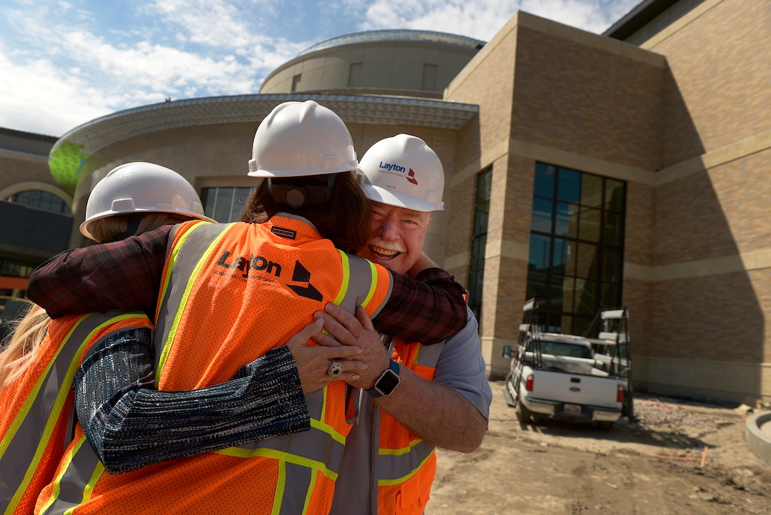 (Leah Hogsten  |  The Salt Lake Tribune) Sandy City Mayor Tom Dolan laughs as Hale Centre Theatre vice president Sally Dietlein (center) hugs him and Sandy City communications director Nicole Martin (left) on the theatre's construction site. The Mountain American Performing Arts Centre is the new 130,000 square feet home to new Hale Centre Theatre, August 8, 2017. 