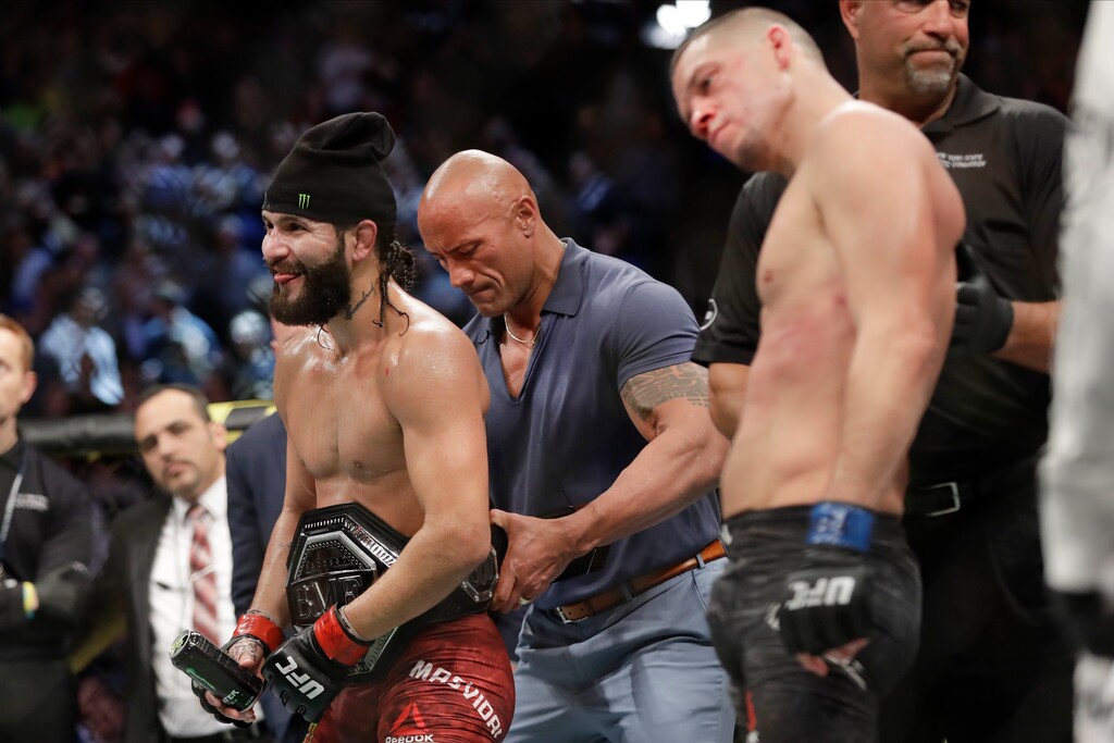 (Frank Franklin II | AP file photo) Actor Dwayne "The Rock" Johnson, center, placed the "BMF" belt on Jorge Masvidal, left, after he defeated Nate Diaz at UFC 244 in, November 2019. Masvidal will in turn place the belt on the winner of the headlining bout between Dustin Poirier and Justin Gaethje at UFC 291 in Salt Lake City, when the "BMF" title is contested for just the second time.