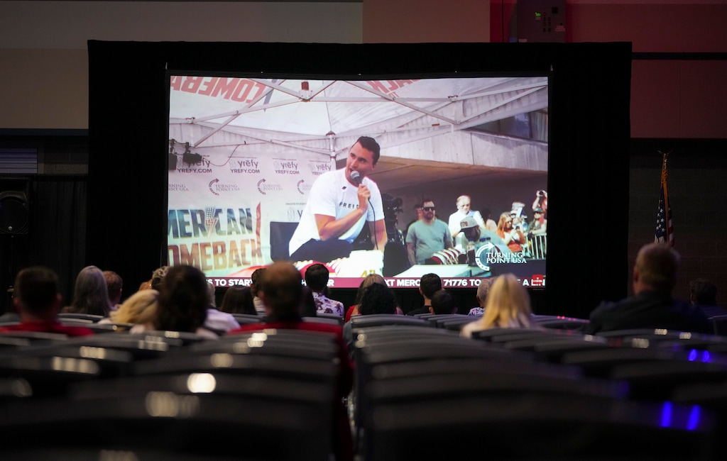 (Bethany Baker | The Salt Lake Tribune) Charlie Kirk, at the last event he held at Utah Valley University, appears on screen as people watch the memorial services for Charlie Kirk during an event at the Utah Valley Convention Center in Provo on Sept. 21, 2025.